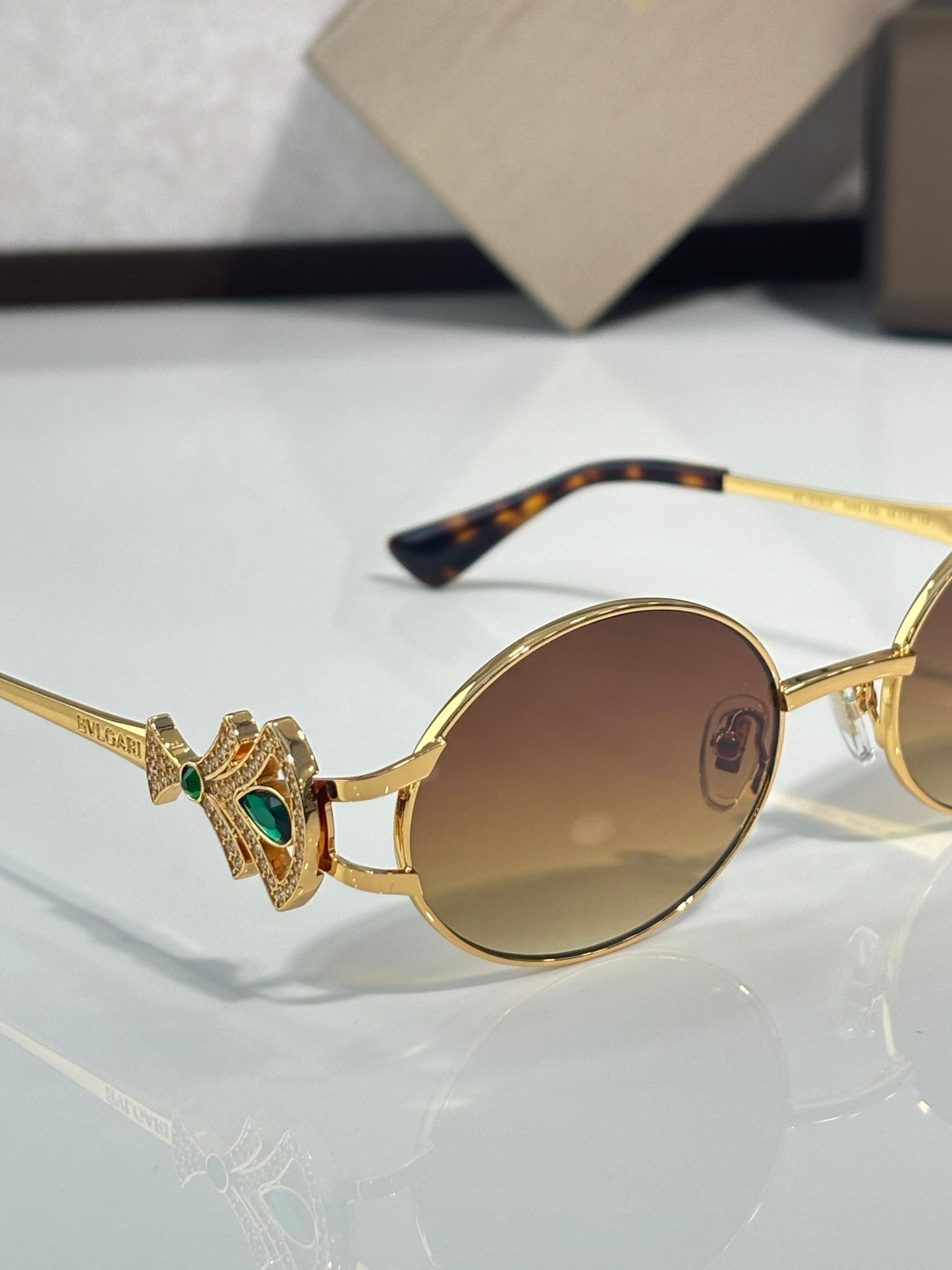 Round sunglasses with gold frame, brown tinted lenses, jeweled temple detail