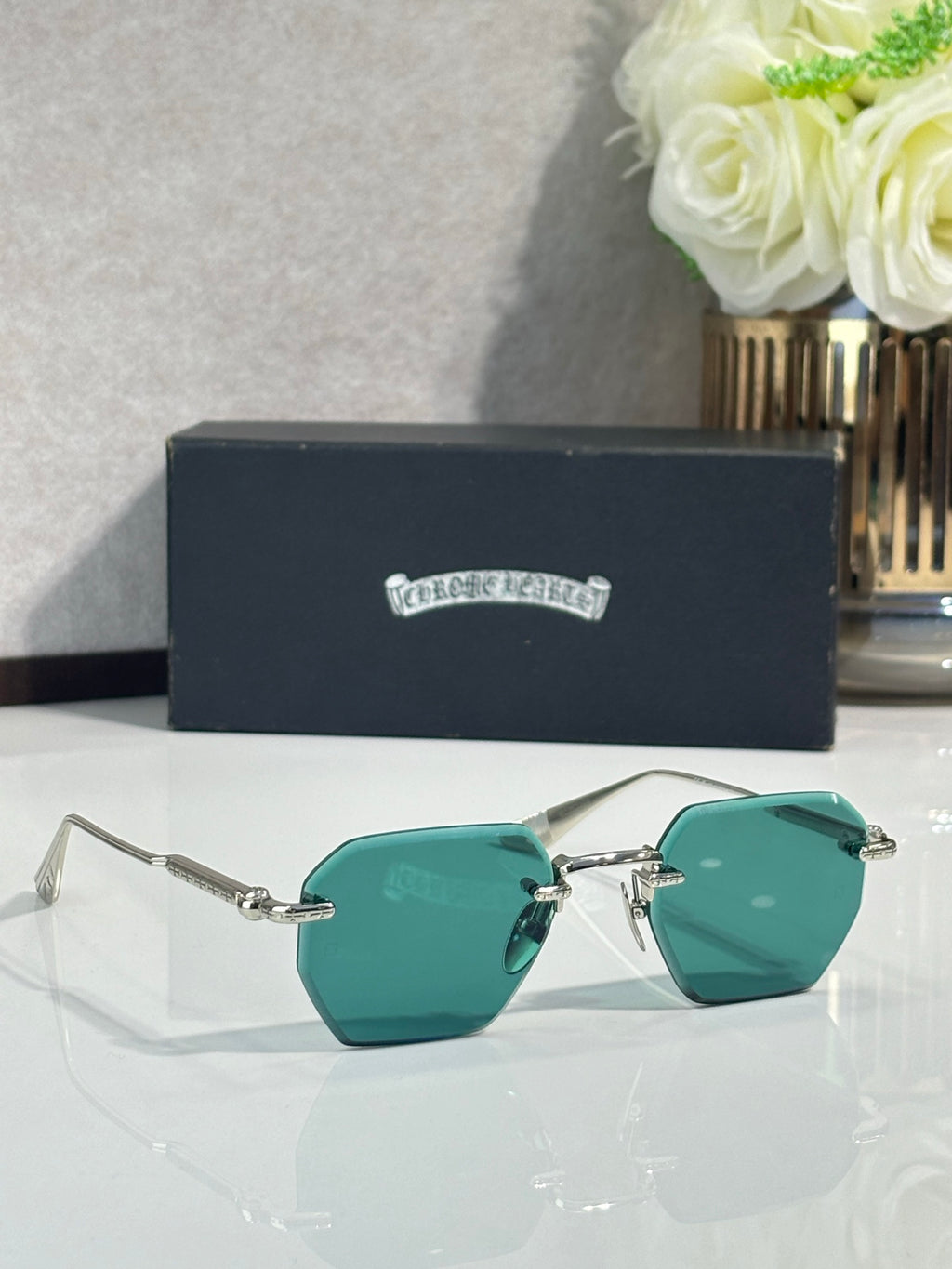 Chrome glasses with gold frame and teal tinted lenses, metal arms and hinge detail