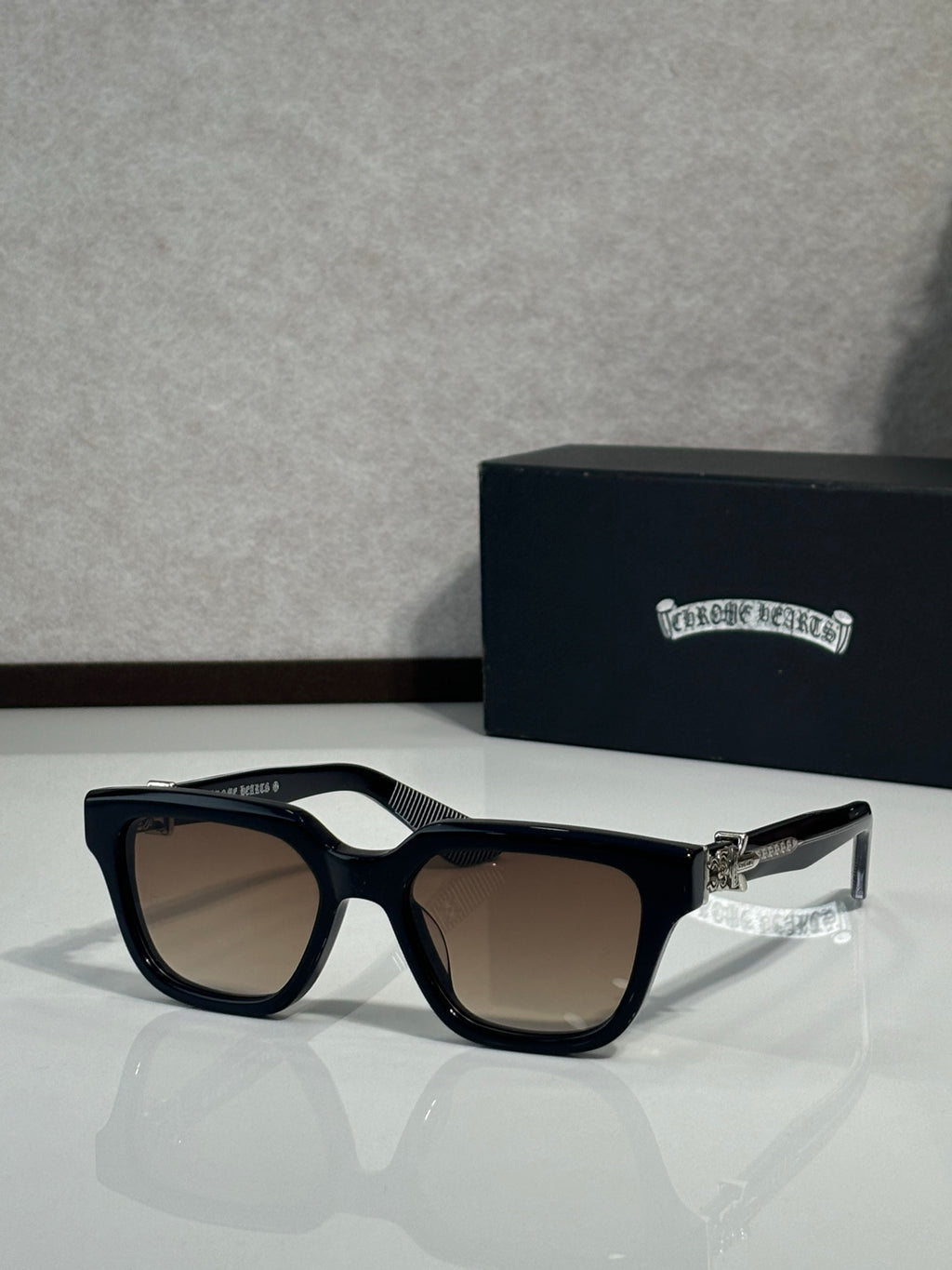 Sunglasses with black frames and taupe-tinted lenses, metal hinge detail on temples