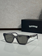 Sunglasses with clear gray frames and dark lenses, black temple accents and gold hinge