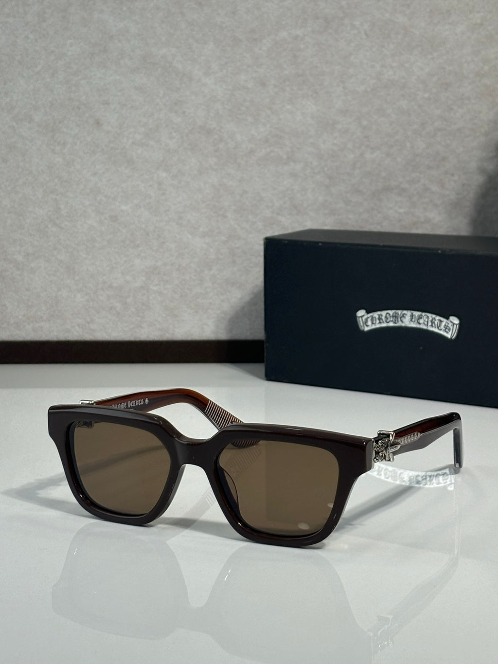 Sunglasses with black frames and warm brown lenses, gold hinge detail at temples
