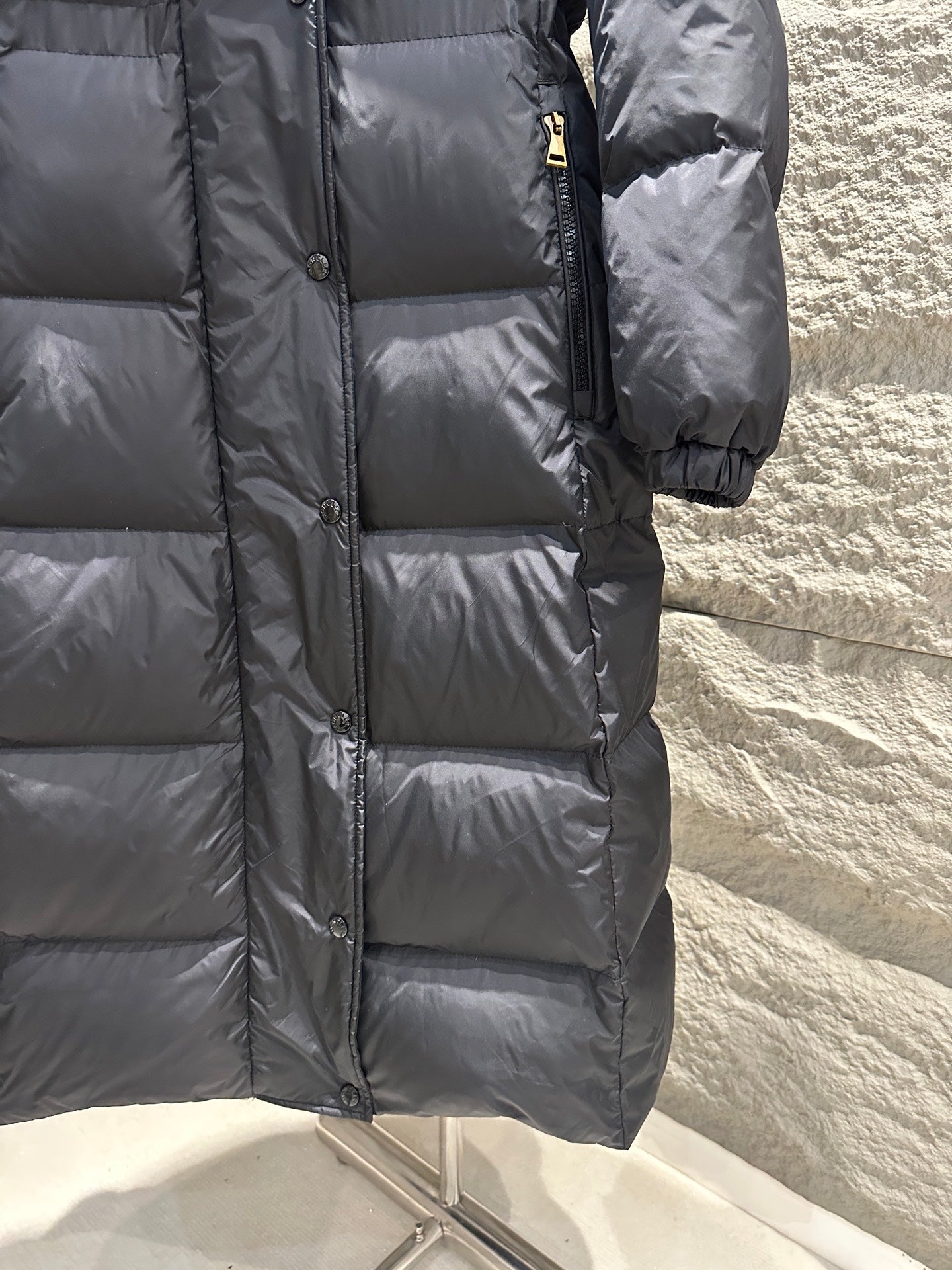 Dark Moncler long puffer coat close-up with front zipper and quilted panels