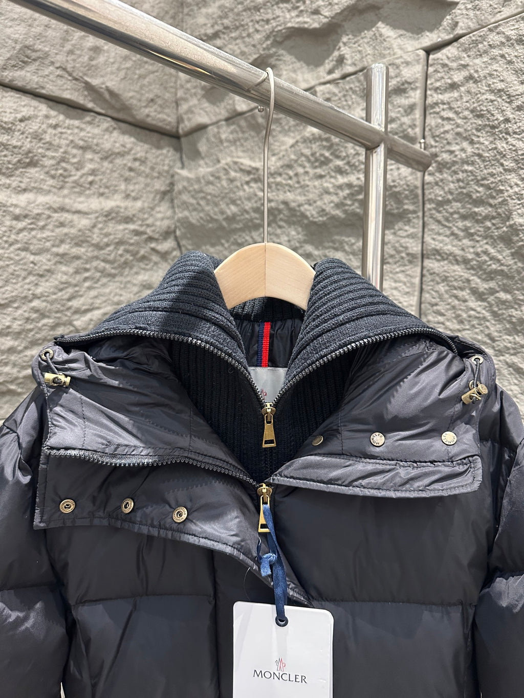 Dark Moncler puffer coat hood close-up with gold buttons and front zipper