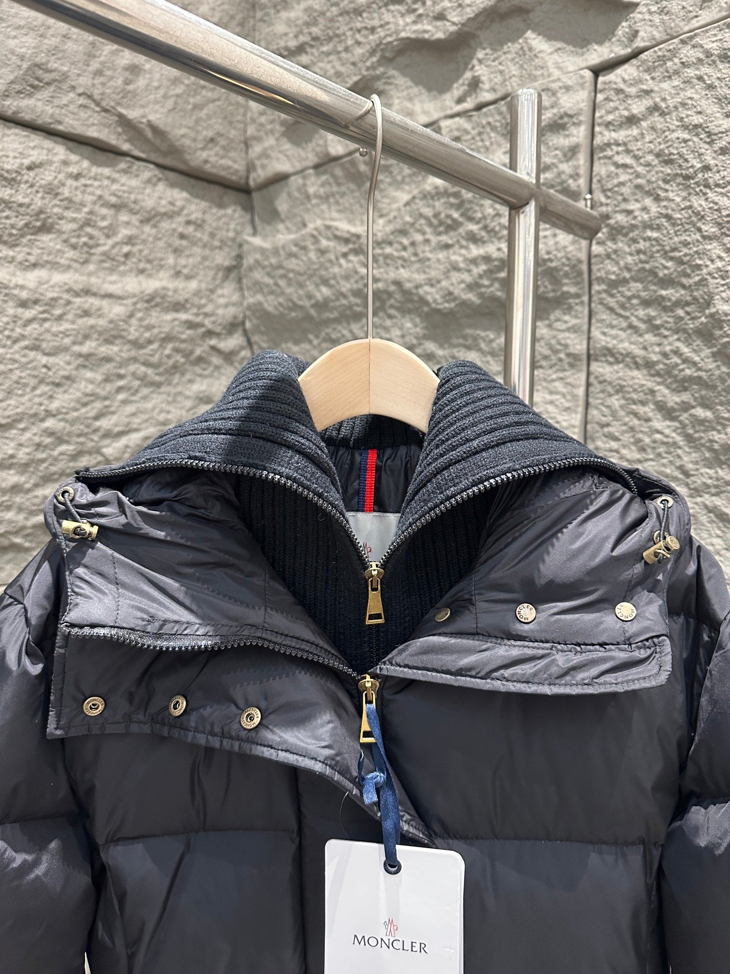 Dark Moncler puffer coat hood close-up with gold buttons and front zipper