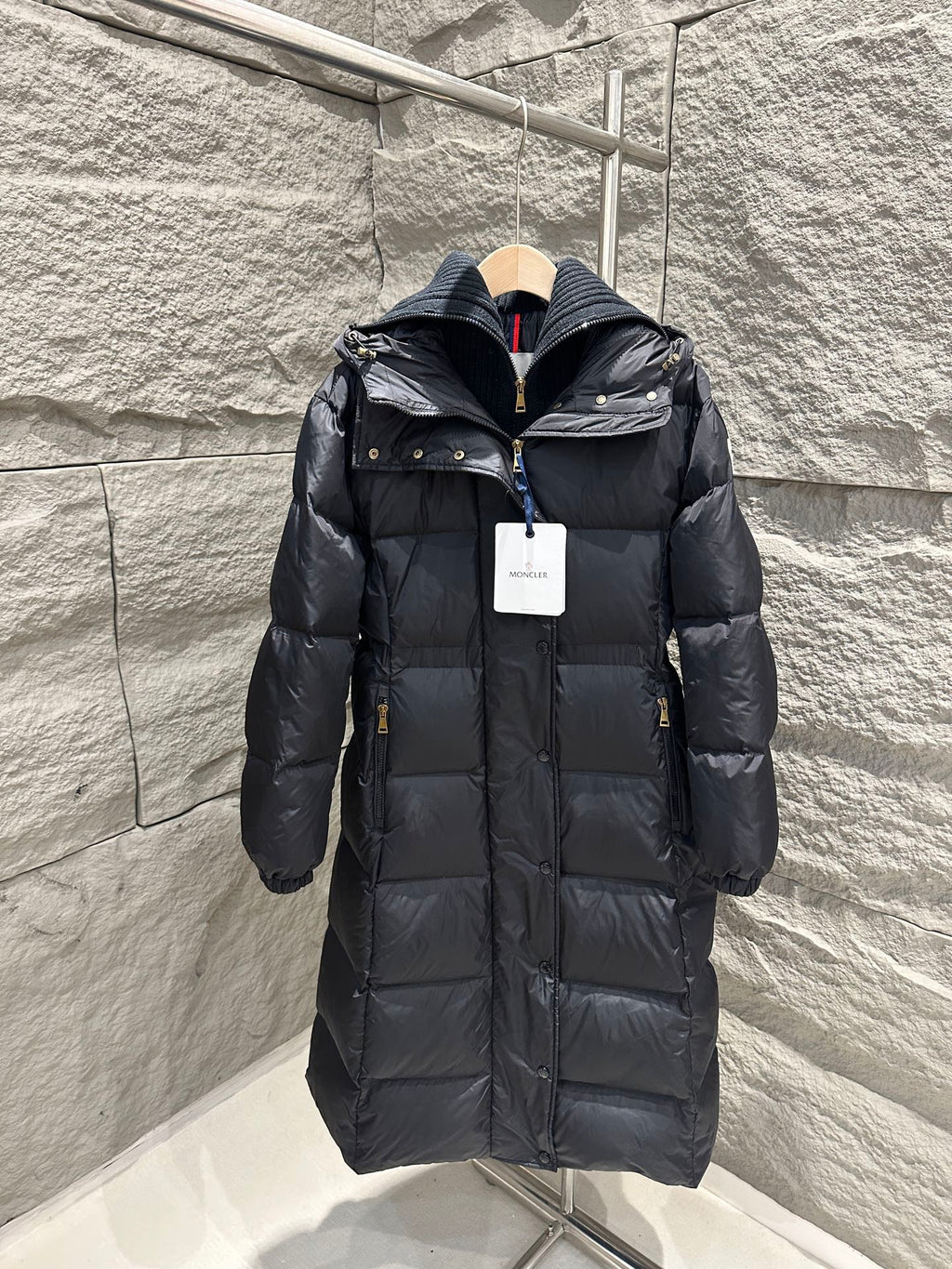 Dark Moncler long puffer coat with hood, front zipper, and quilted stitching