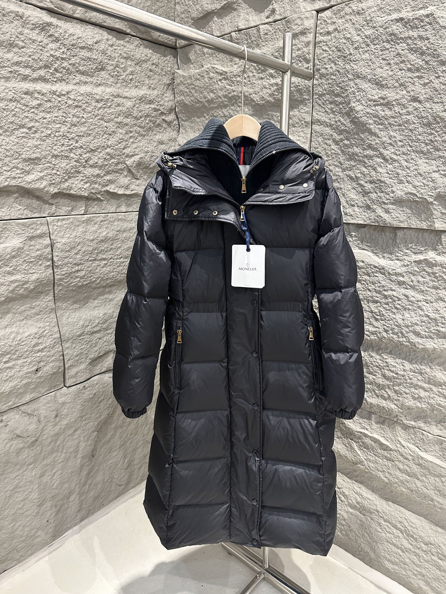 Dark Moncler long puffer coat with hood, front zipper, and quilted stitching
