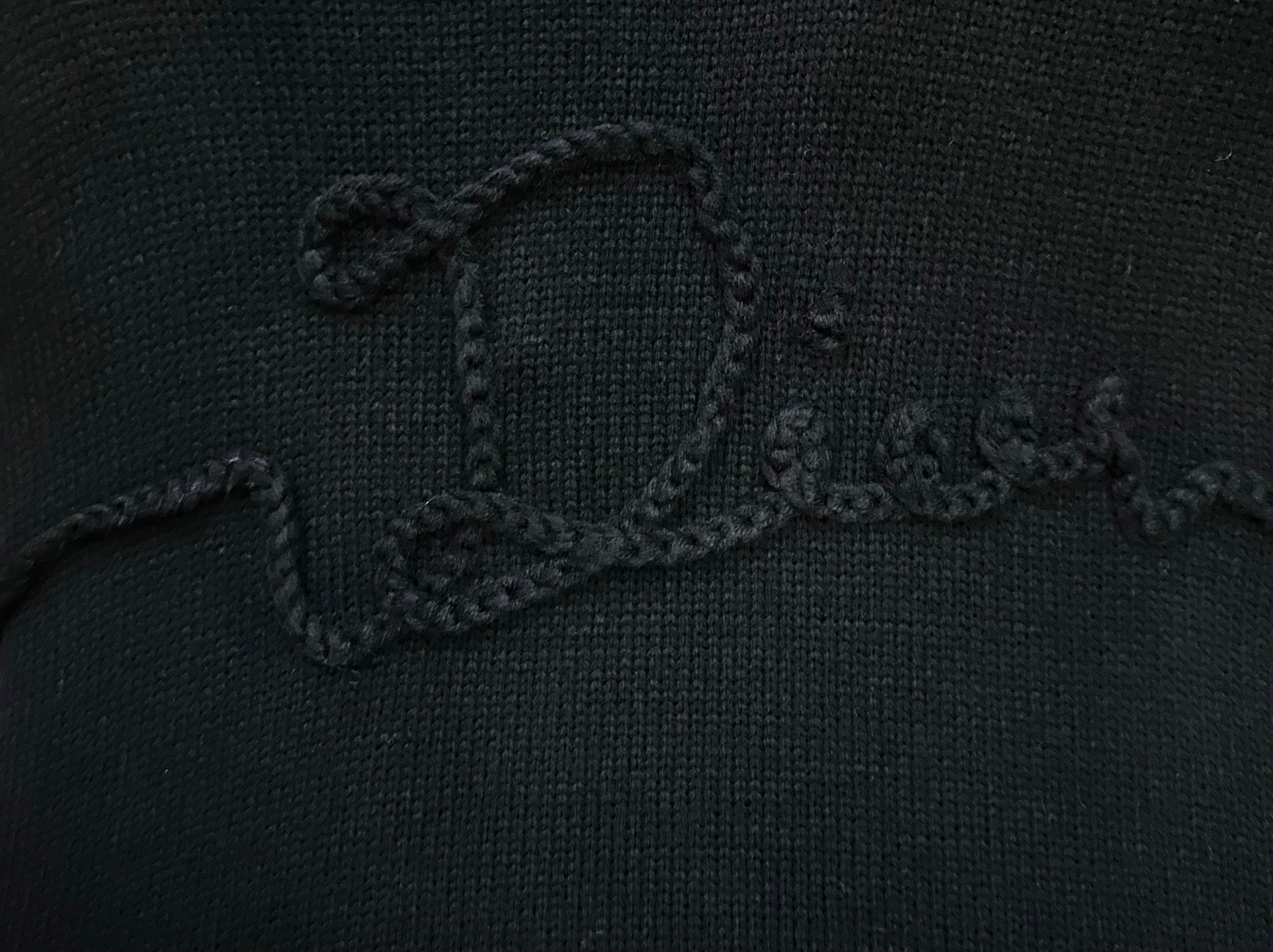 Embroidered script logo detail on black knit sweater chest