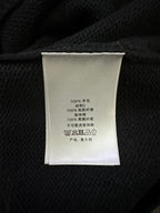Clothing label inside black knit sweater with care text and fabric composition
