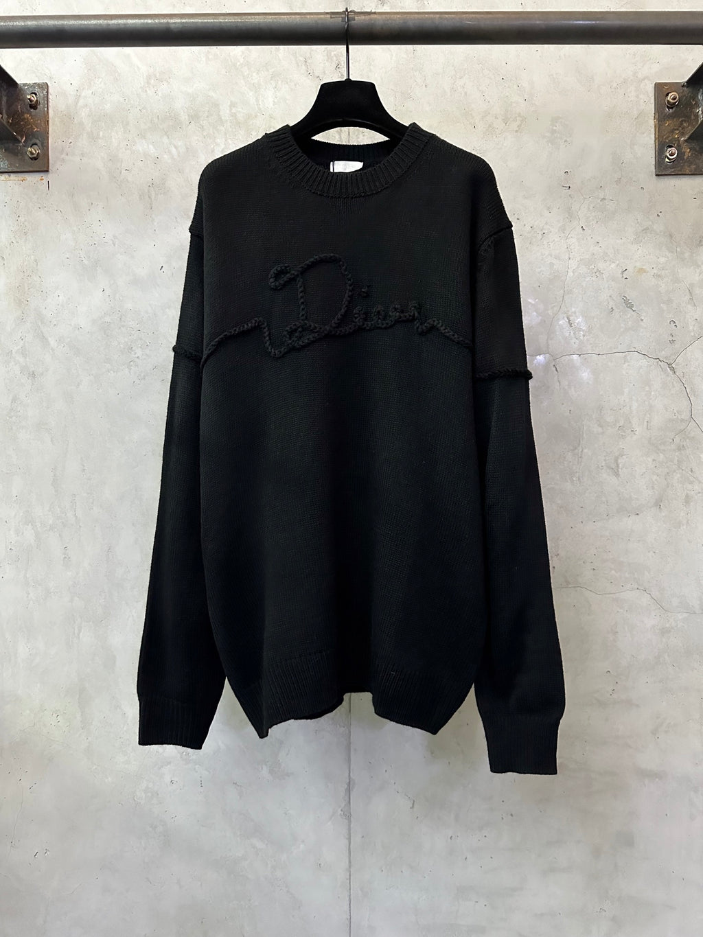 Black long-sleeve knit sweater with crew neck and embroidered logo across chest