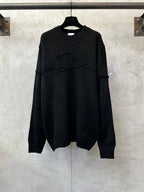 Black long-sleeve knit sweater with crew neck and embroidered logo across chest