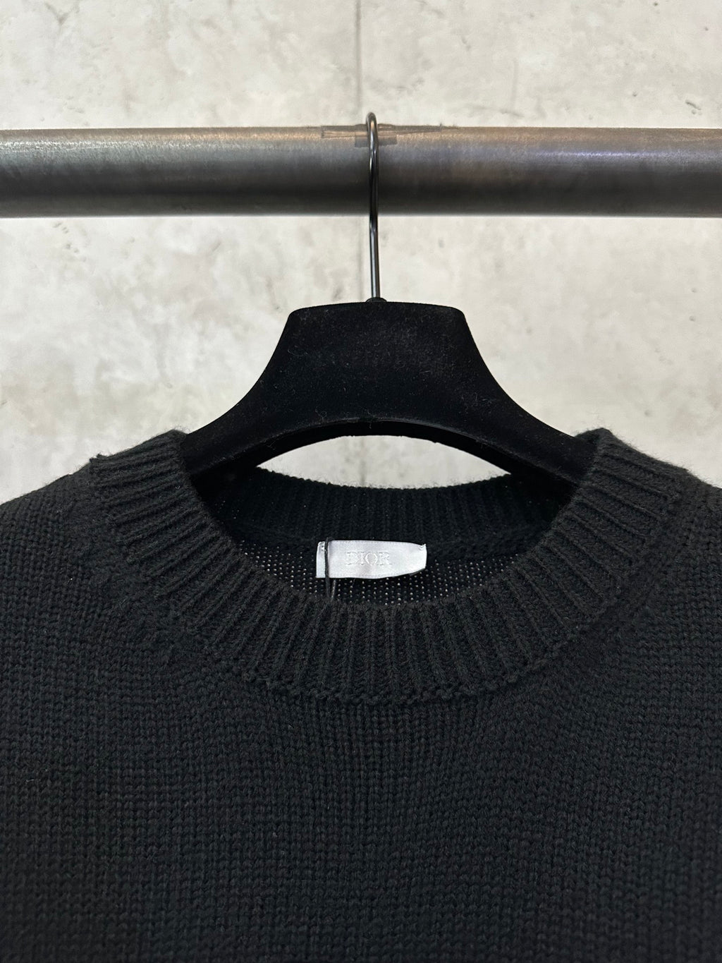 Black crew-neck knit sweater close-up with ribbed collar and inside neck label