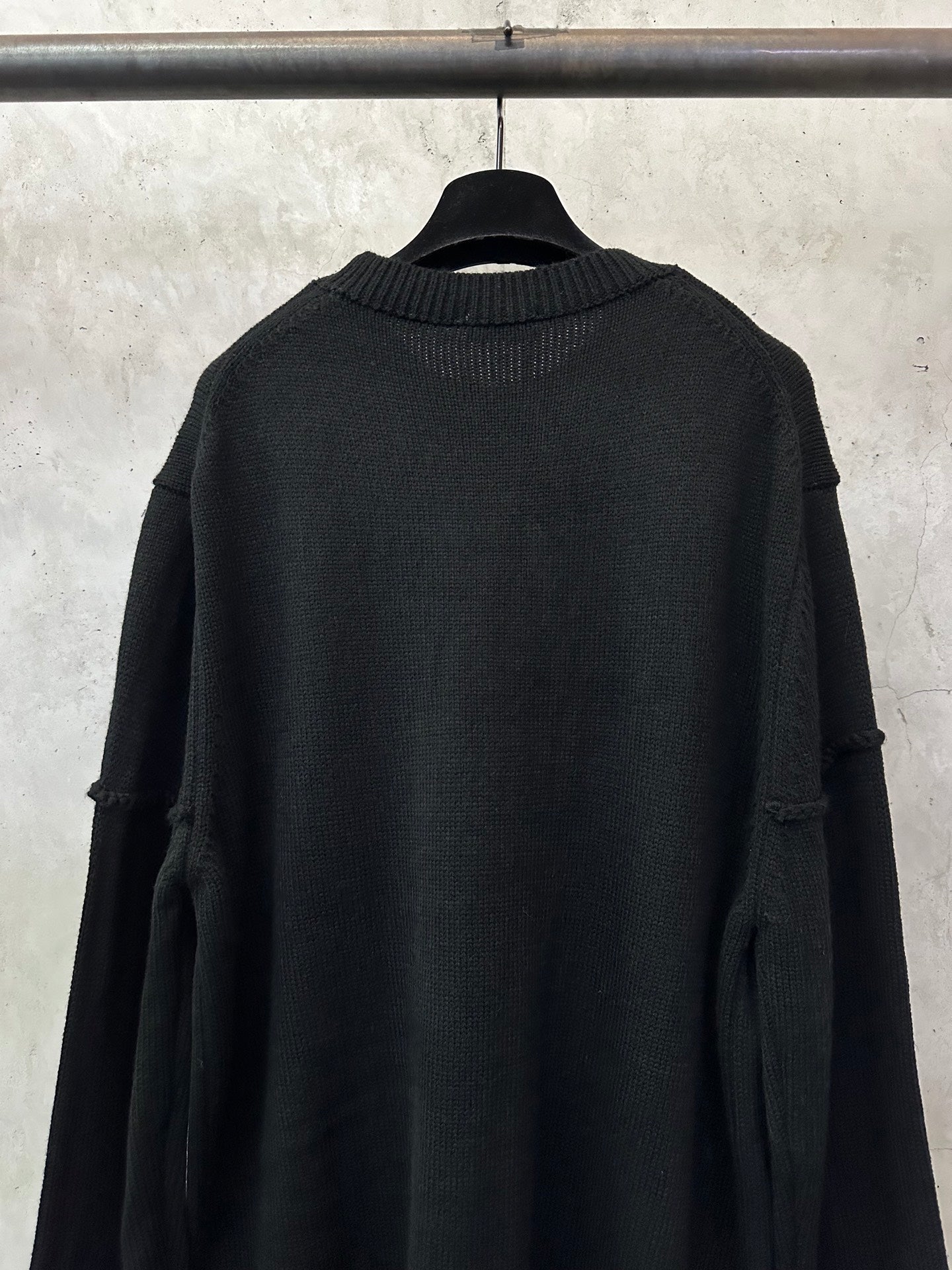 Black knit sweater back view with crew neck ribbing and folded shoulder detail