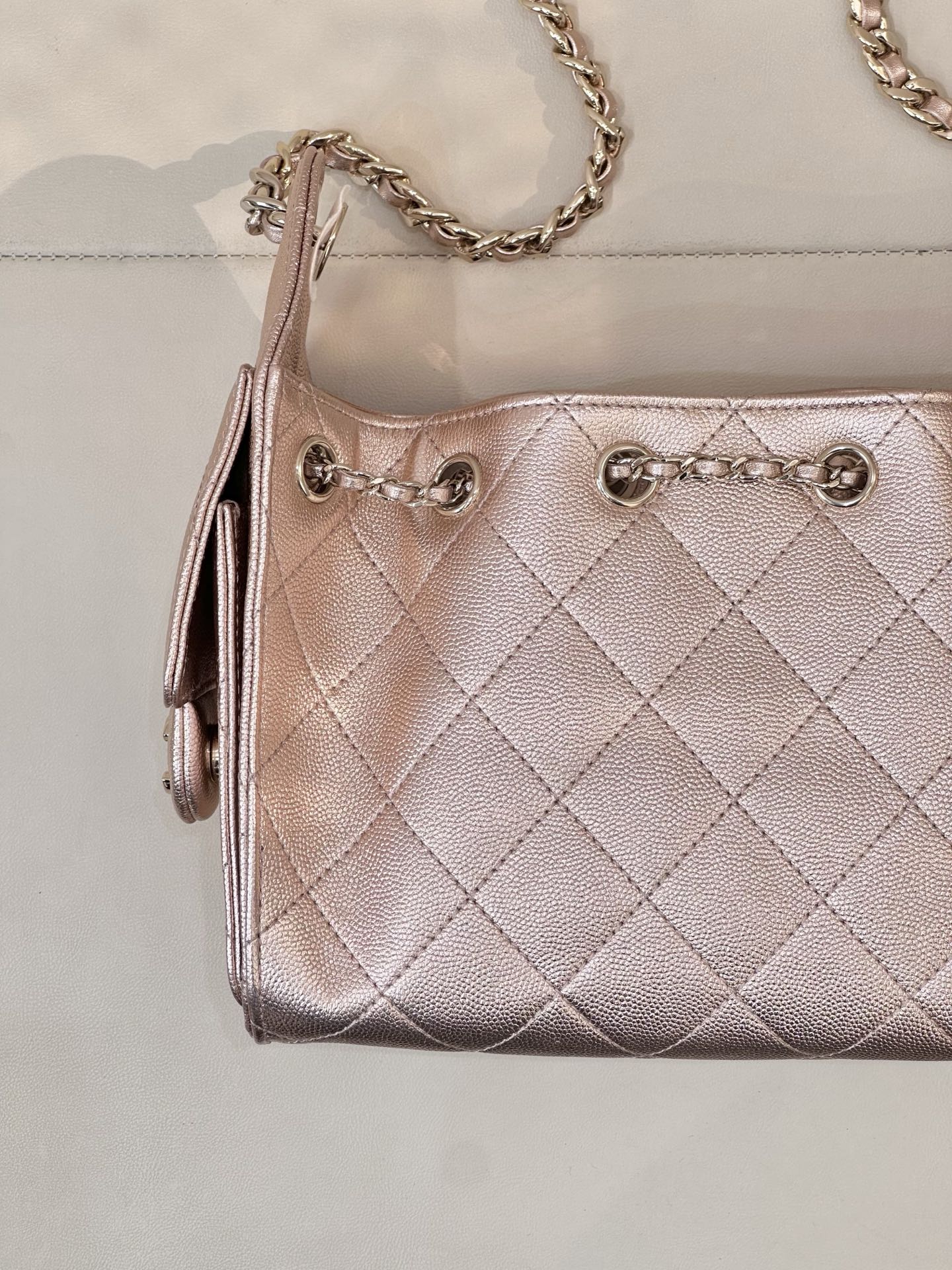 Chanel quilted handbag front panel close-up, rose-pink leather, CC logo and chain detail