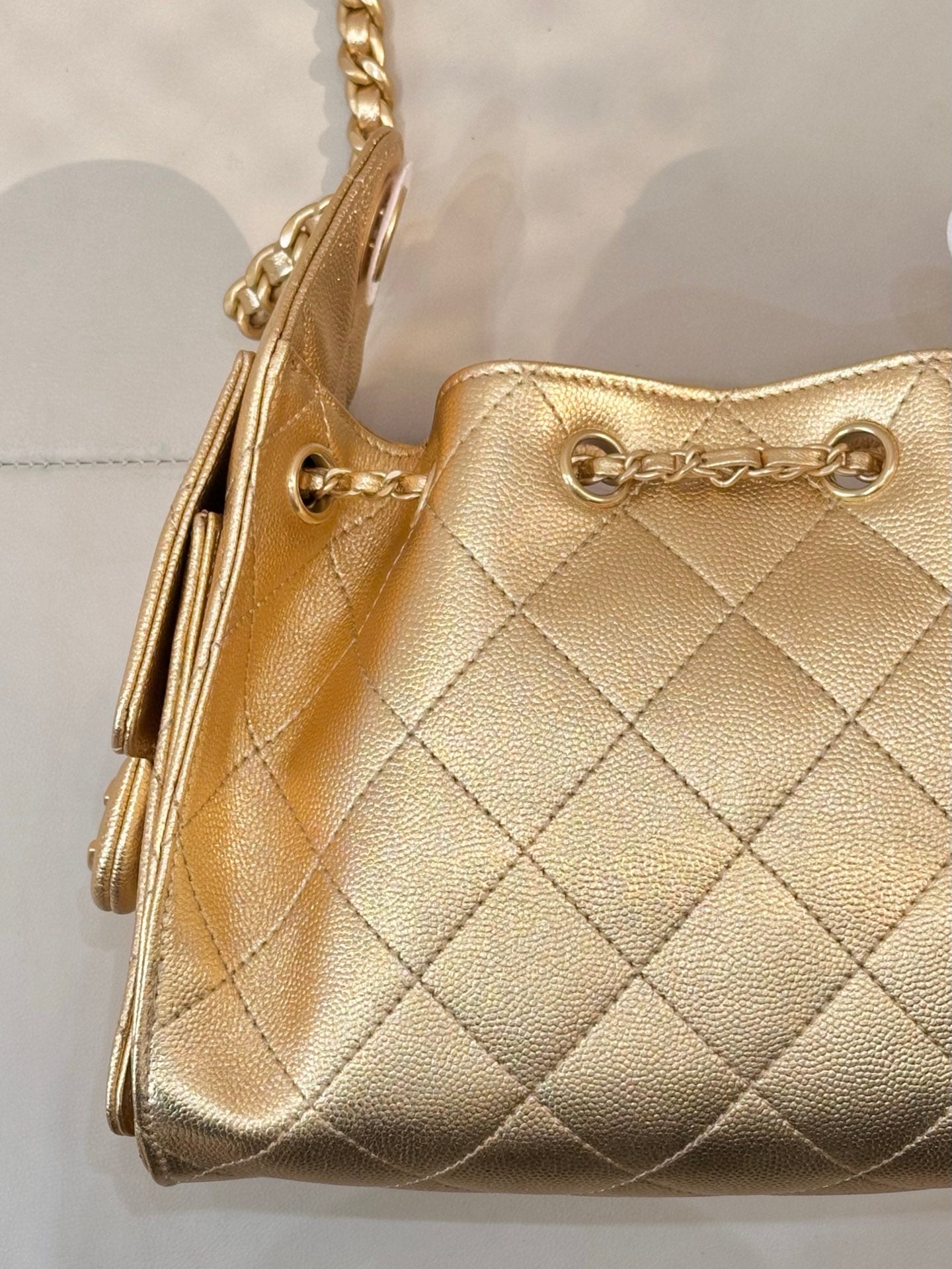 Chanel quilted gold handbag close-up of front flap, chain strap, and ring hardware