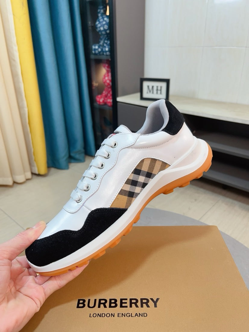 White lace-up sneaker with black toe, beige plaid side insert, and orange sole