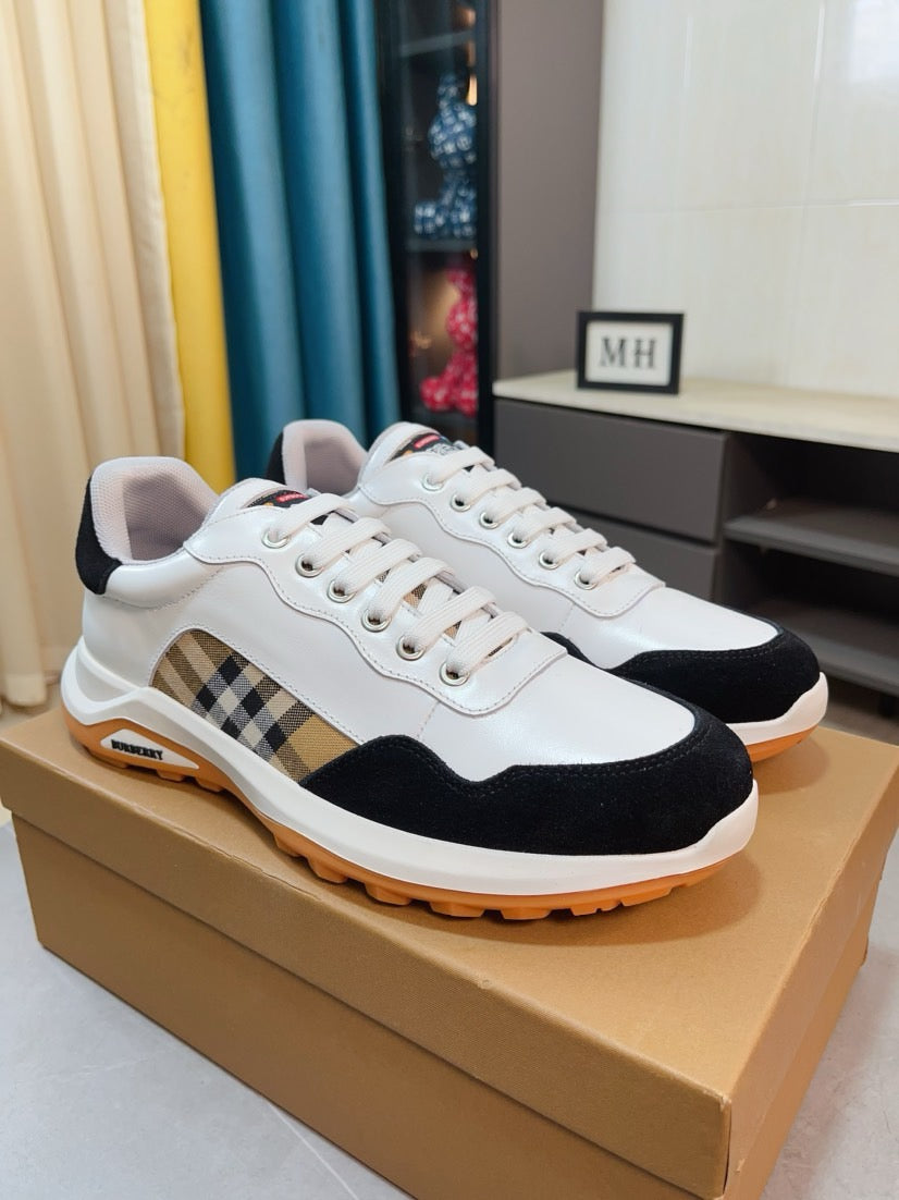 Pair of white and dark sneakers with plaid side stripe and orange rubber sole