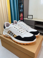 Pair of white and dark sneakers with plaid side stripe and orange rubber sole