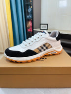 White lace-up sneakers with dark toe, beige plaid side insert, and orange rubber sole