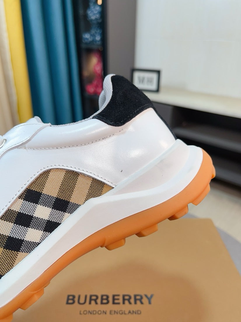 Side view close-up of white sneaker with beige plaid insert and orange sole