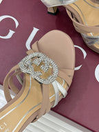 Gucci heeled sandal detail: crystal-style heart buckle with silver straps on light beige