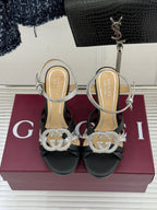 Gucci heeled sandals with black uppers and silver straps, featuring rhinestone G-style detail