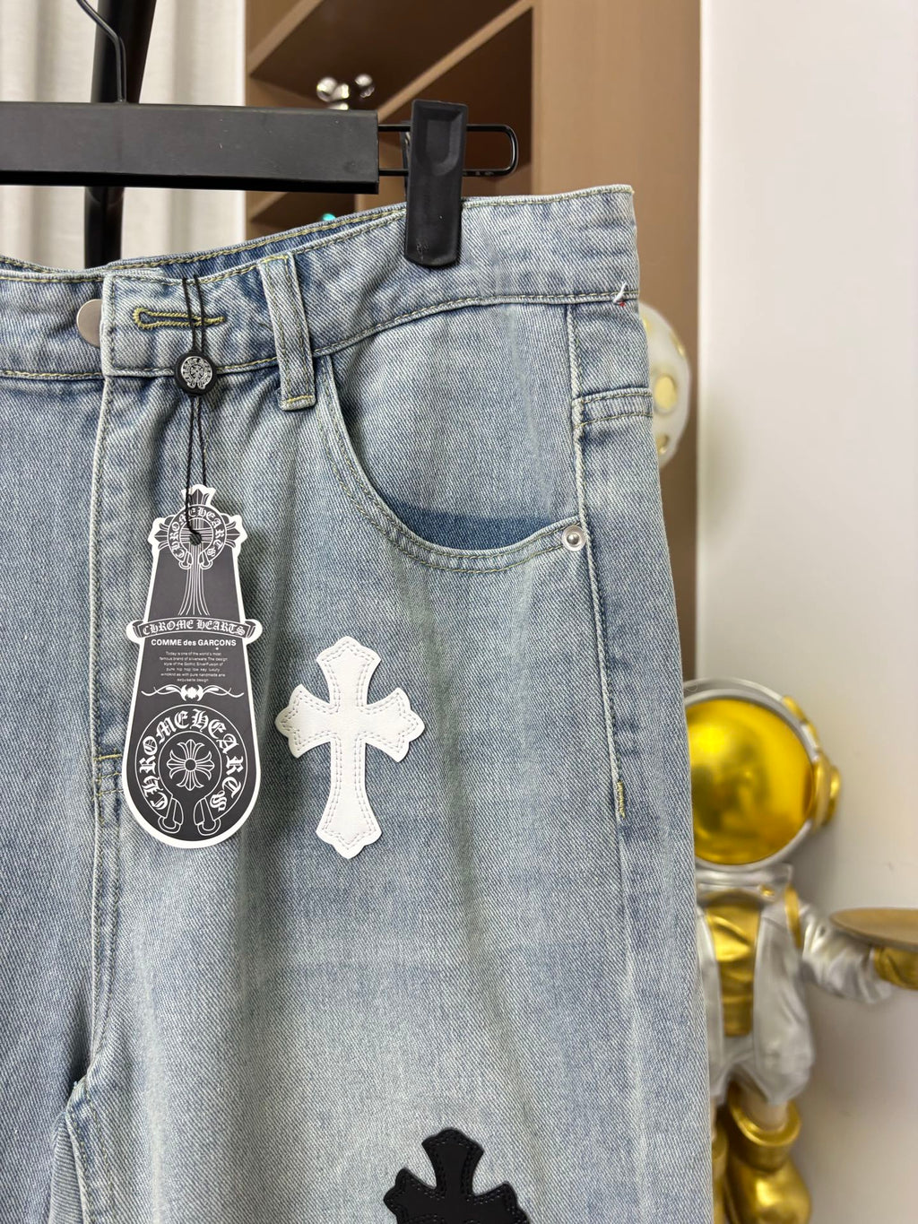 Light wash denim pants with belt loops and hanging cross and charm details