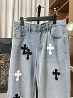 Light wash denim pants with button fly and black cross patches