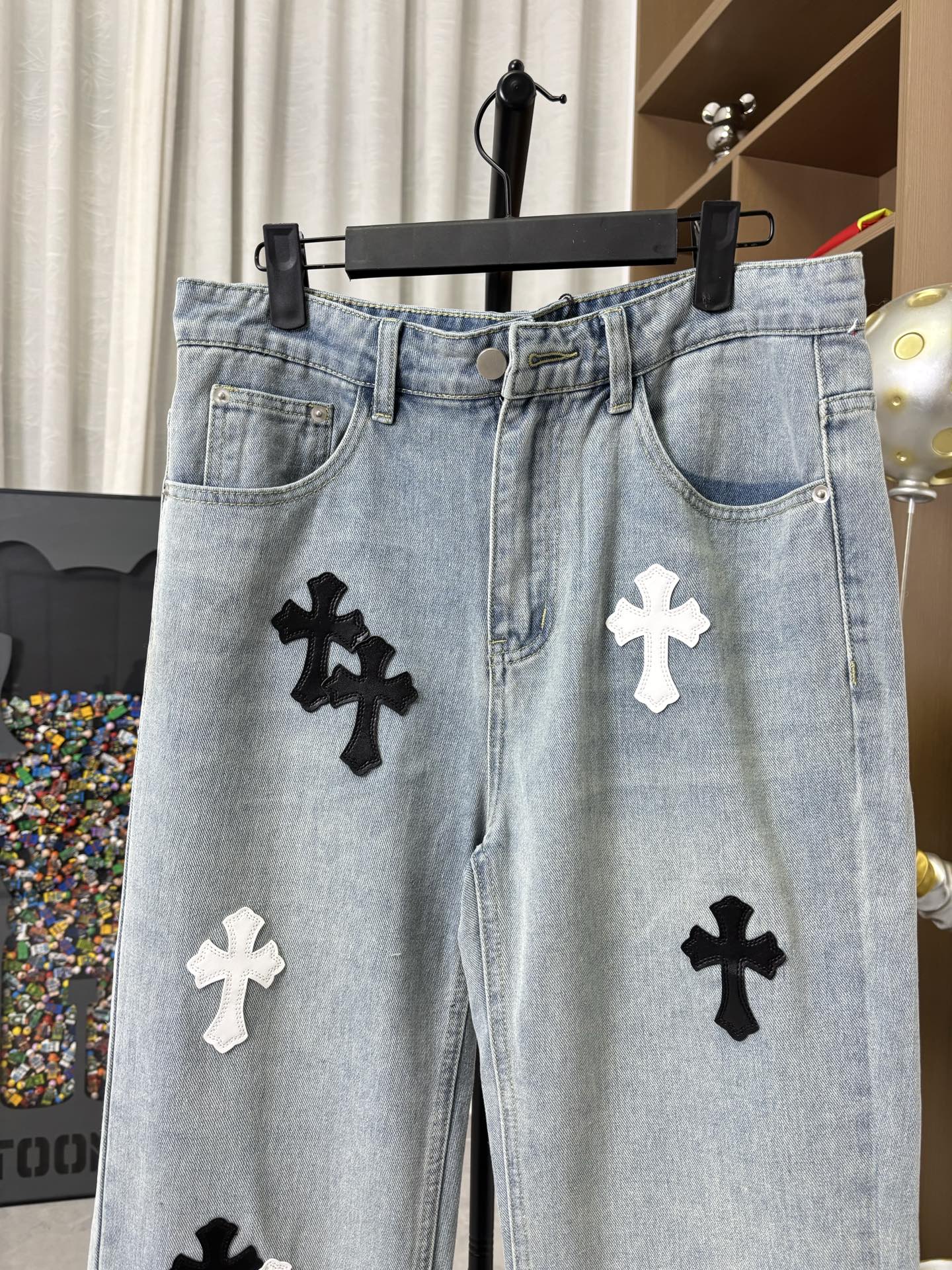 Light wash denim pants with button fly and black cross patches