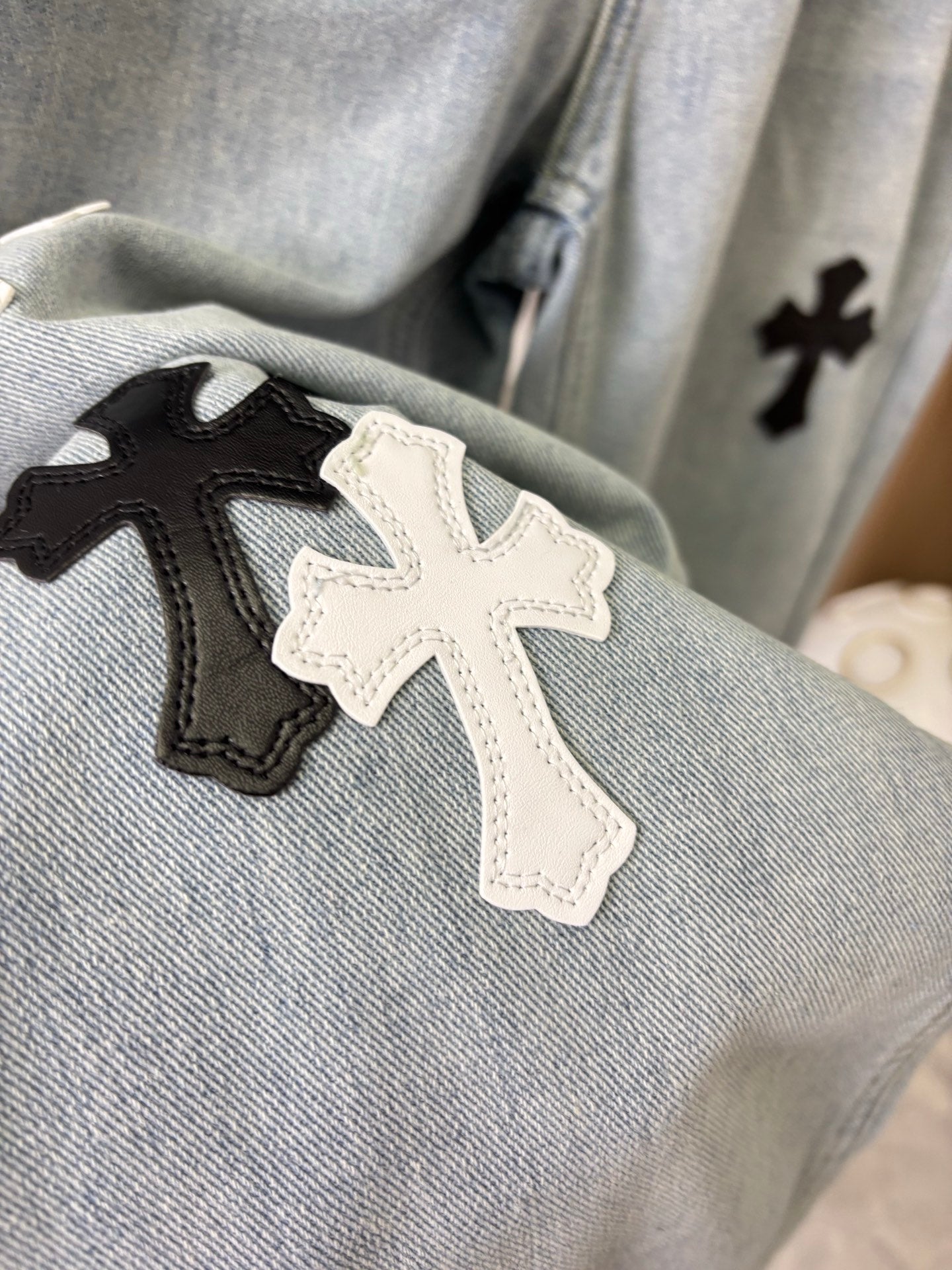 Close-up of cross patches on light wash denim pant fabric
