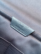 Louis Vuitton brand label on navy textured leather strap near stitching