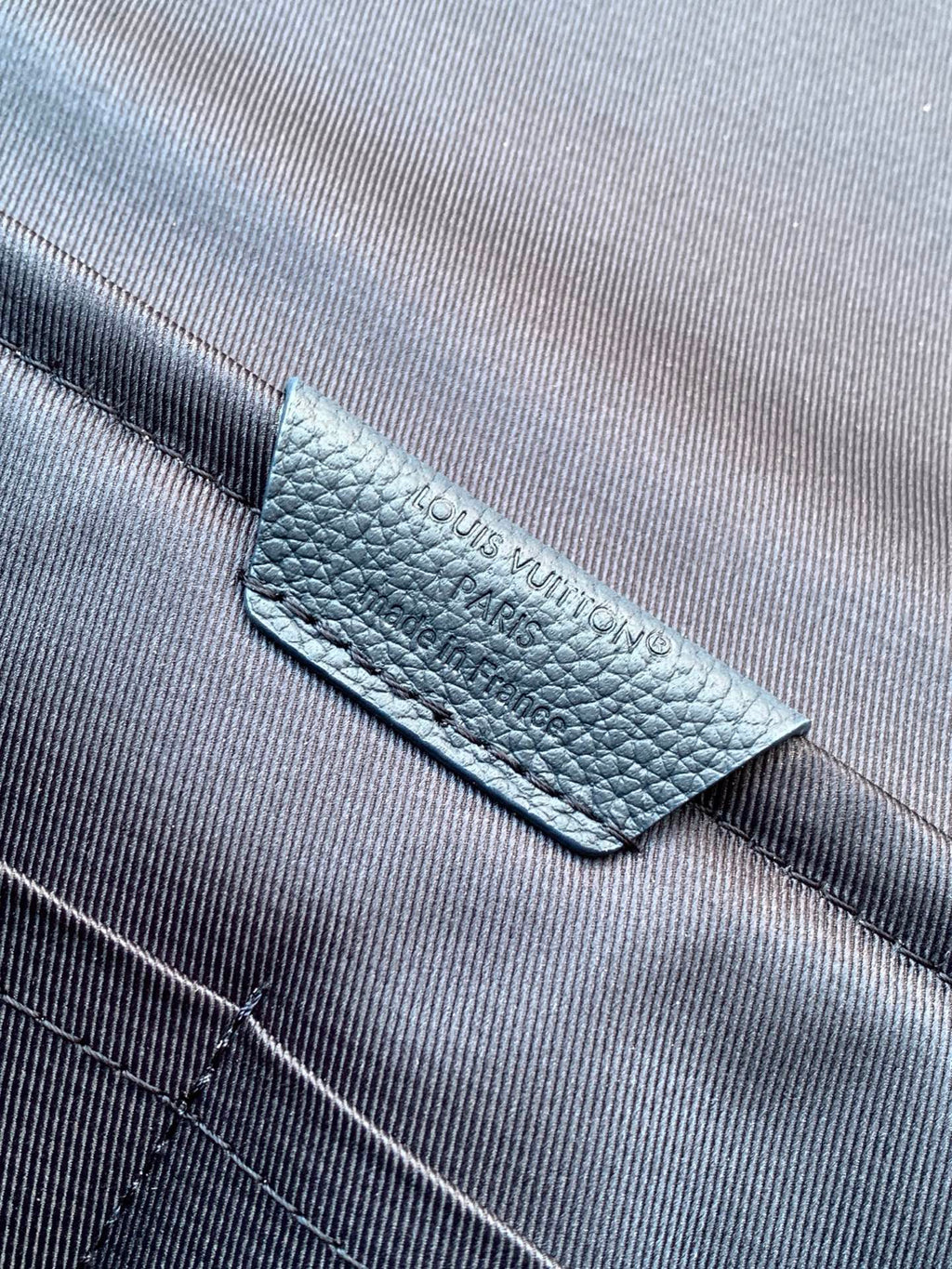 Blue Louis Vuitton bag label on textured leather strap