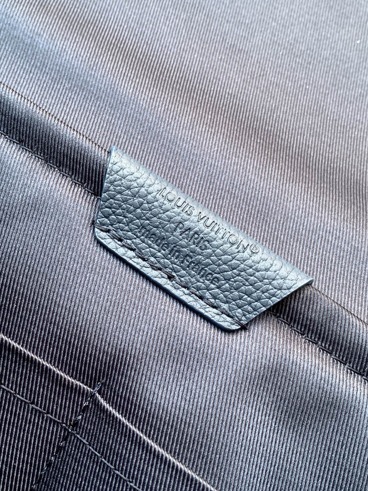 Blue Louis Vuitton bag label on textured leather strap