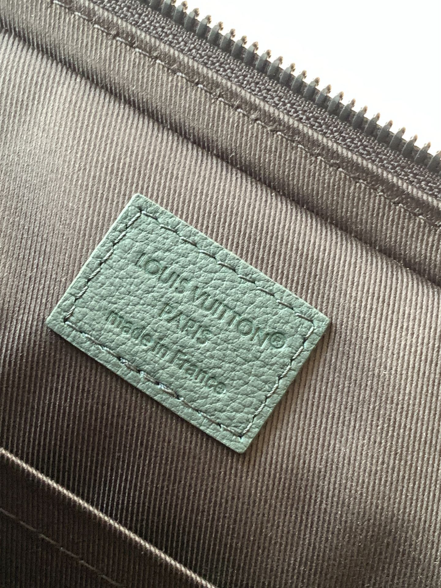 Louis Vuitton green leather label on brown interior lining fabric