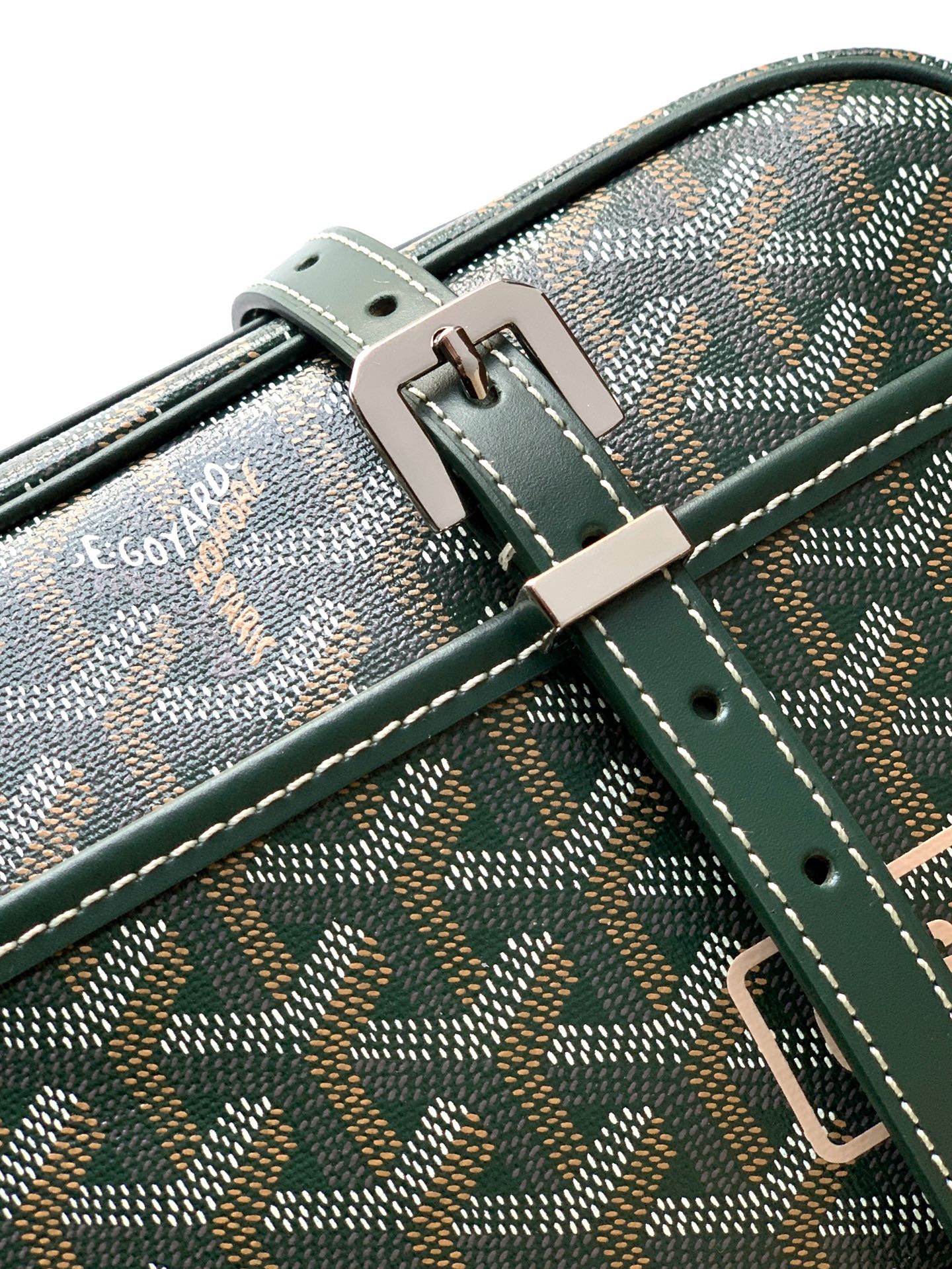 Green patterned bag close-up with front strap buckle and stitched crossbody handle