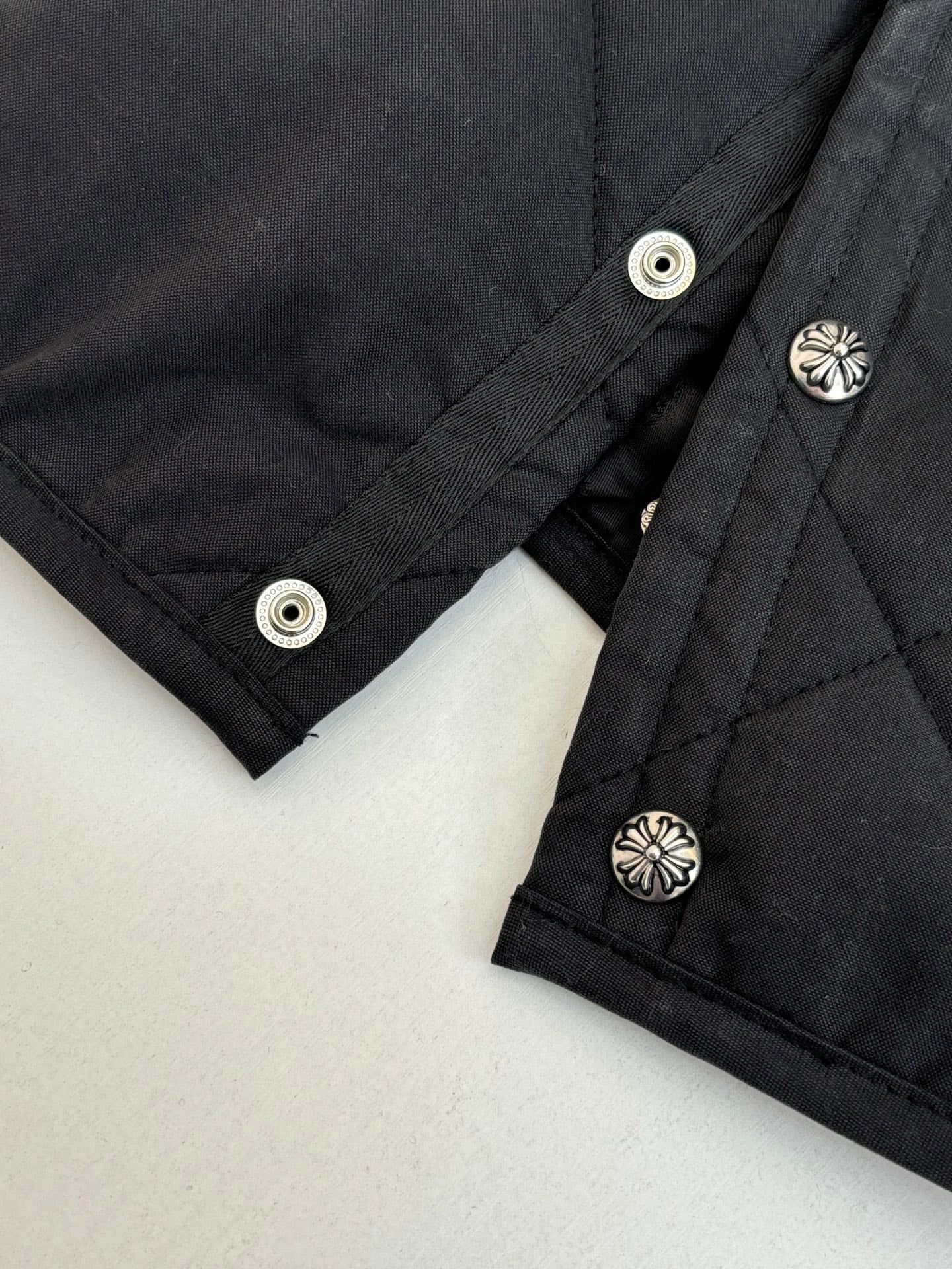 Black quilted jacket cuffs with snap buttons and small silver emblems