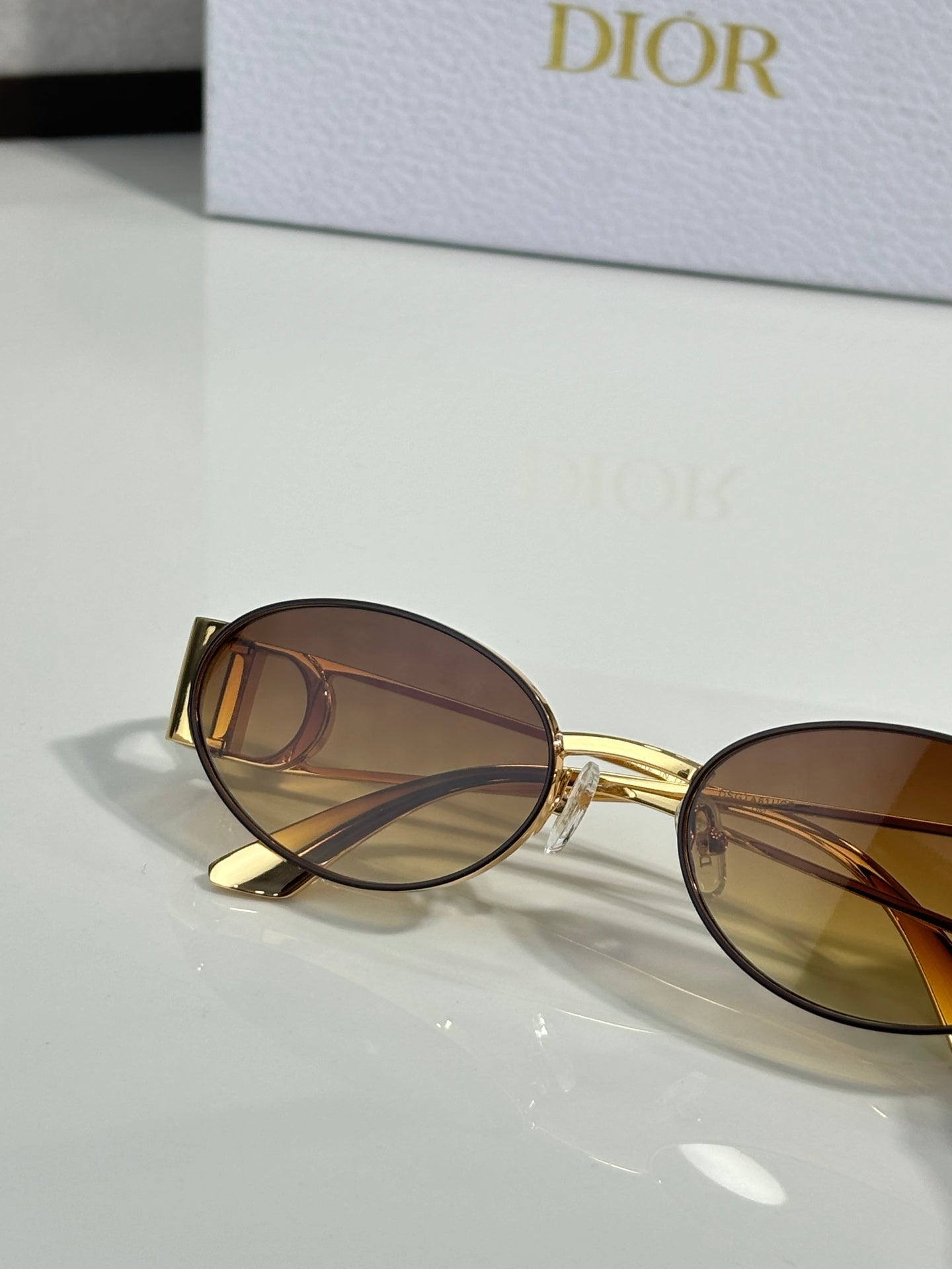 Round dark sunglasses with gold frame and side logo detail