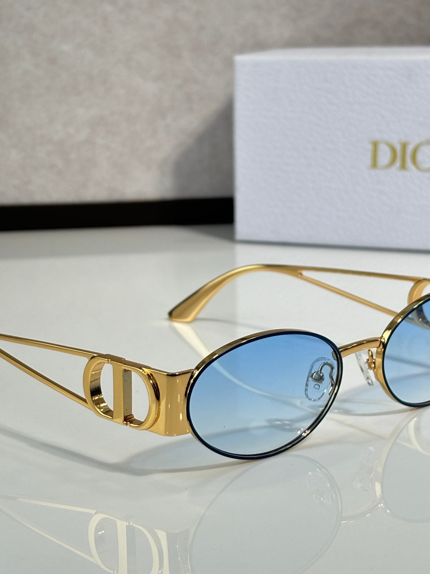 Gold round sunglasses with blue tinted lens and logo temple