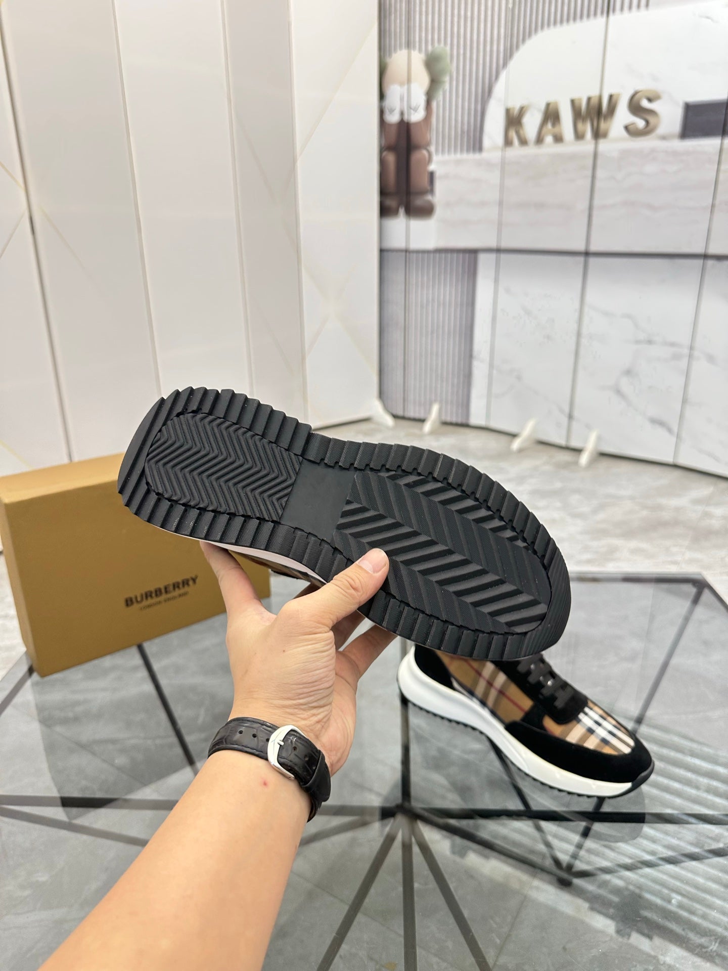 Burberry sneaker outsole view: black tread sole with tartan-lined upper
