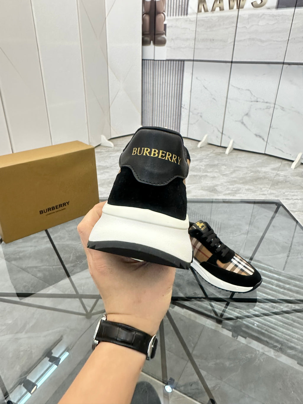 Burberry sneakers from heel view: black upper with Burberry logo patch and white sole