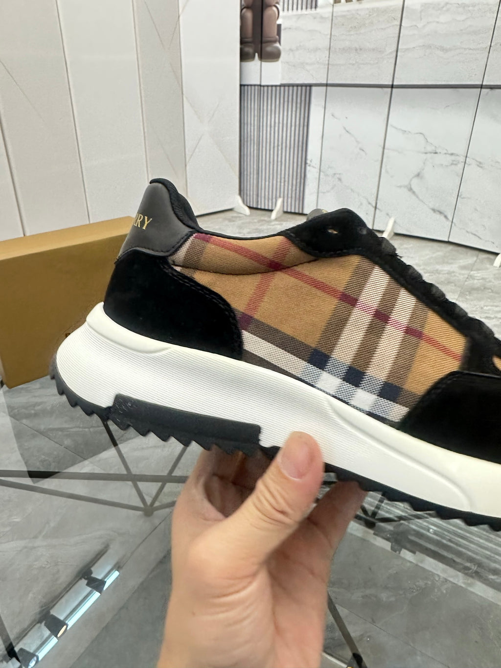 Burberry sneaker profile with tartan side panel, black suede, and white chunky sole