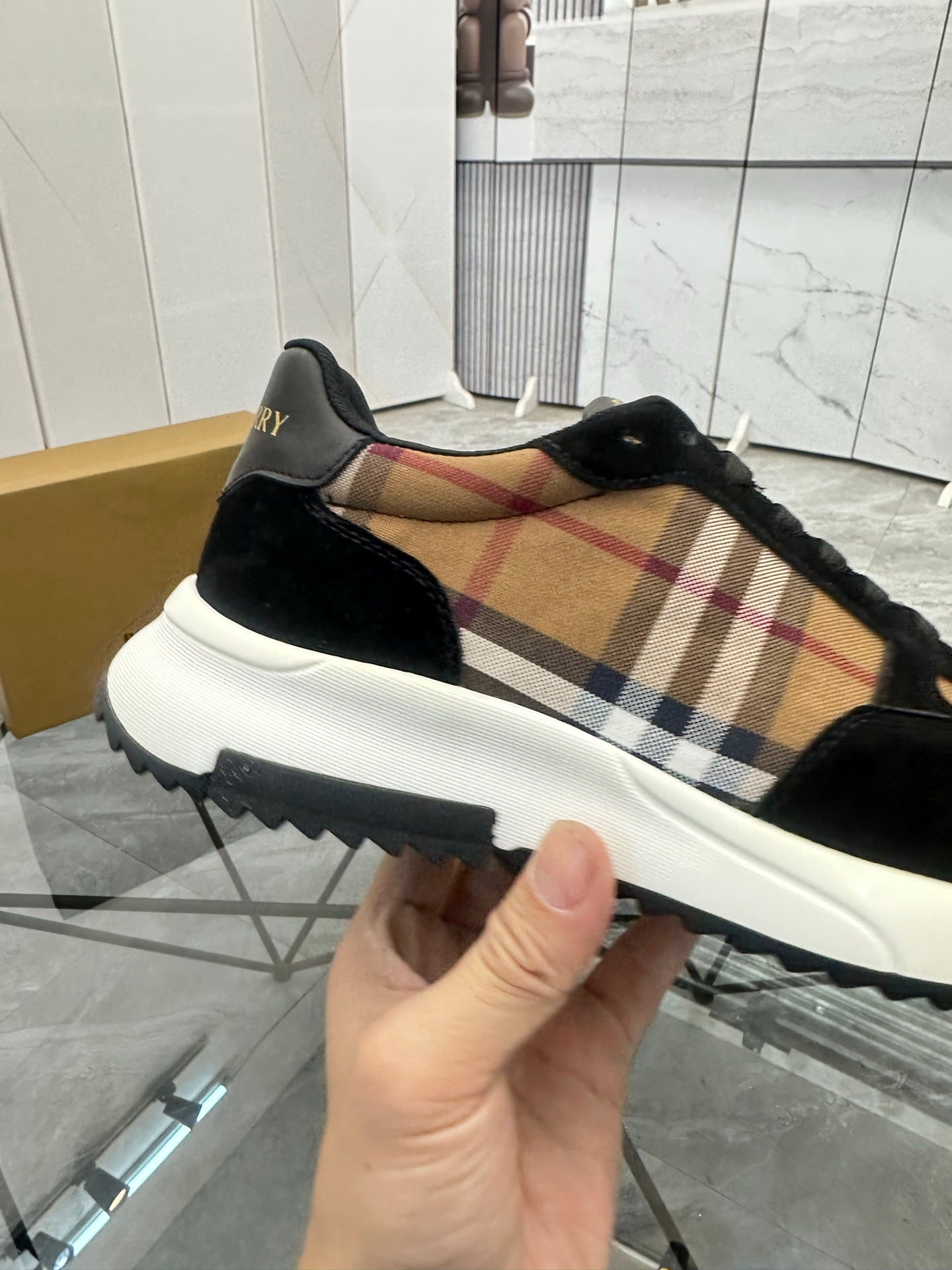 Burberry sneaker profile with tartan side panel, black suede, and white chunky sole