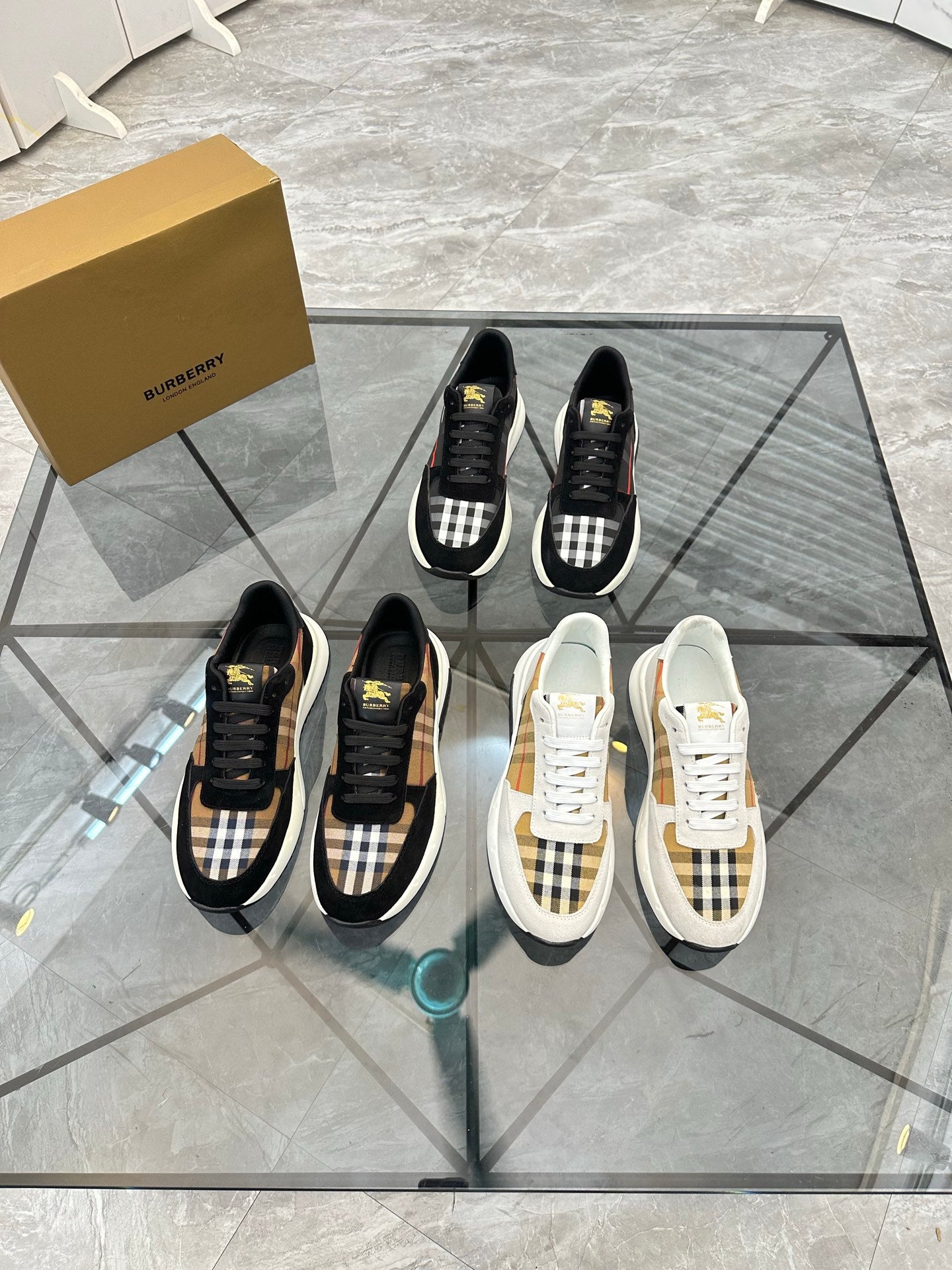 Burberry sneakers display: black tartan pairs and white pairs with lace-up fronts