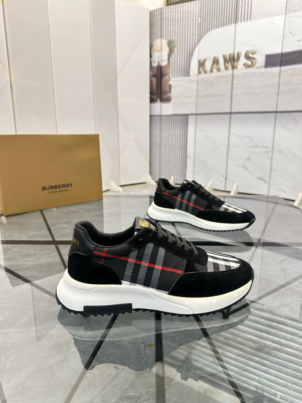 Burberry black lace-up sneakers with red-and-gray plaid stripe detail and white midsole