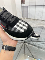 Burberry black sneaker close-up with gray check panel, black laces, and white edge sole
