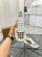 White lace-up sneaker with plaid tongue panel and gold logo at the heel, rubber sole