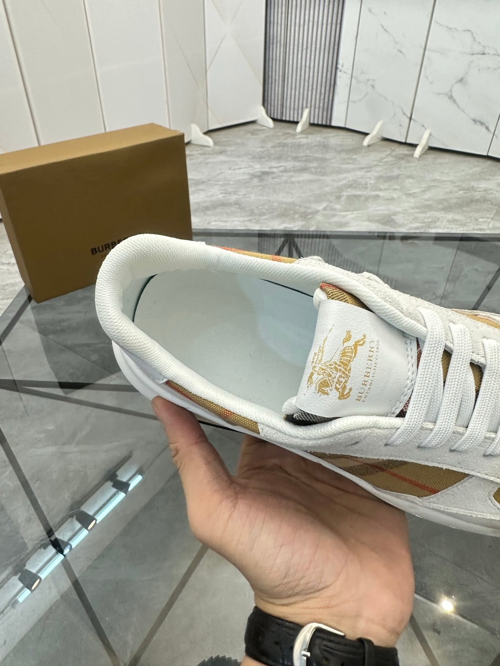 White sneaker interior view showing gold heel logo and white laces, rubber sole