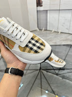 Close-up of white sneaker with plaid side panel and white laces, cushioned sole
