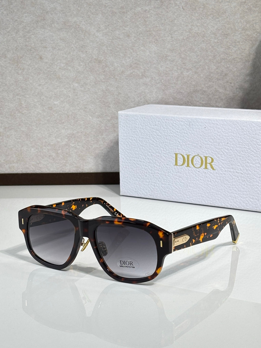 Dior sunglasses with dark tortoise frames, speckled accents, gold logo at temple