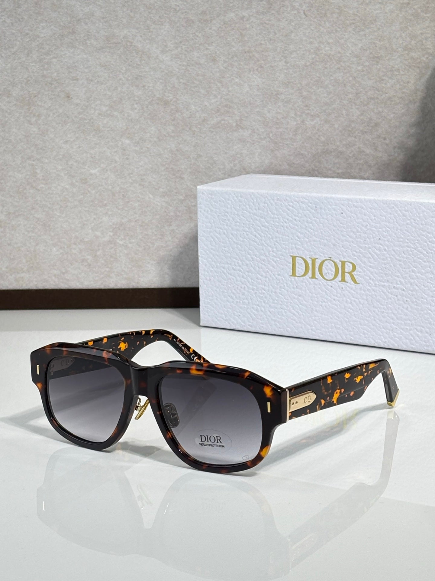 Dior sunglasses with dark tortoise frames, speckled accents, gold logo at temple