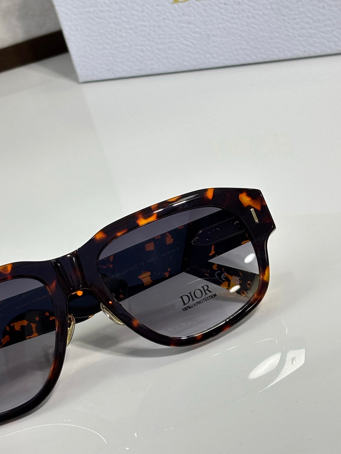 Dior sunglasses close-up: tortoise frame and dark lens with Dior logo